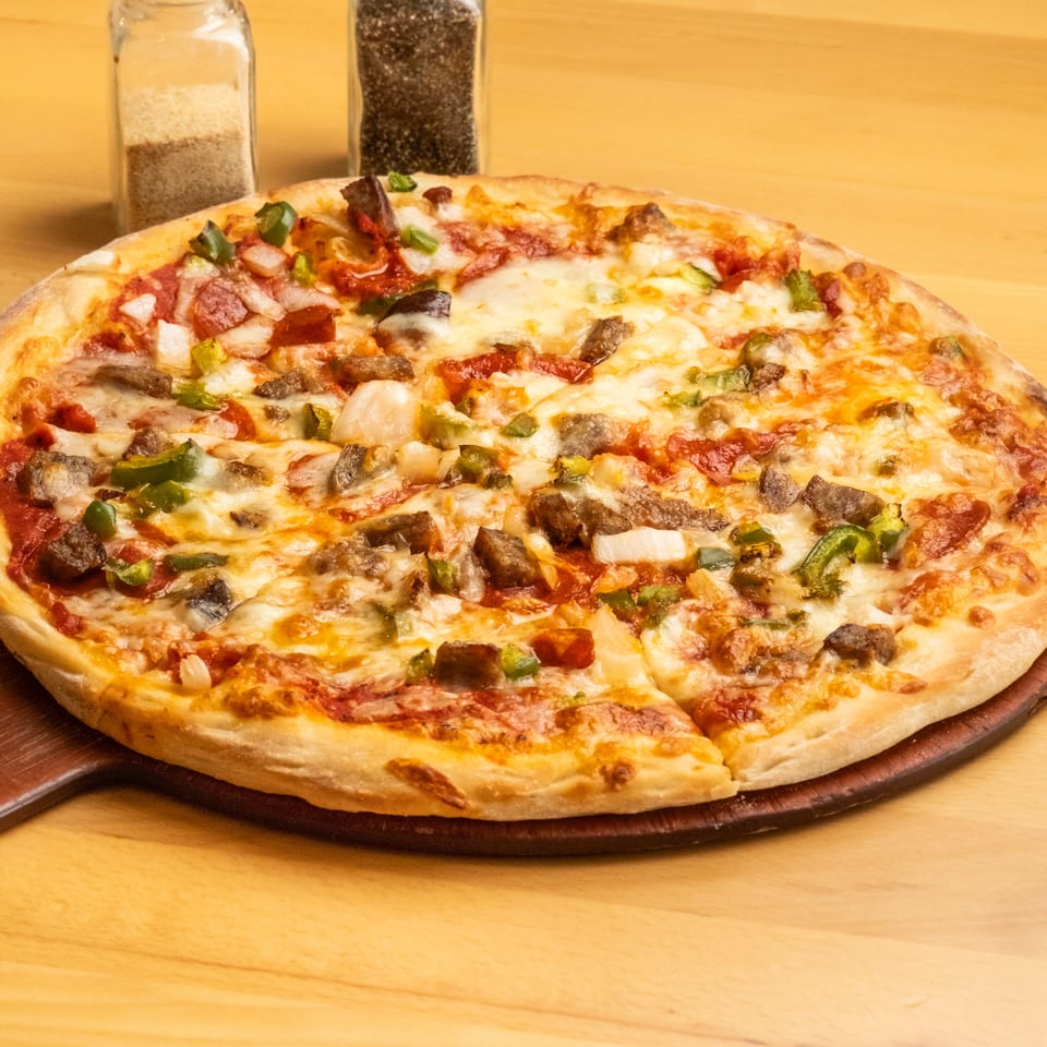 Cheesy pizza topped with pepperoni, mushrooms, green peppers, onions, and sausage on a wooden serving board.