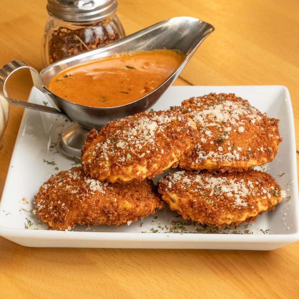 Crispy breaded chicken cutlets topped with grated cheese and herbs, served with tomato sauce on a white plate.